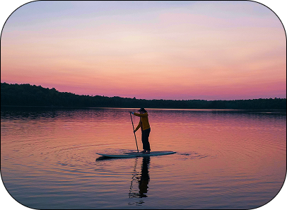 Paddling boarding on lake during sunset